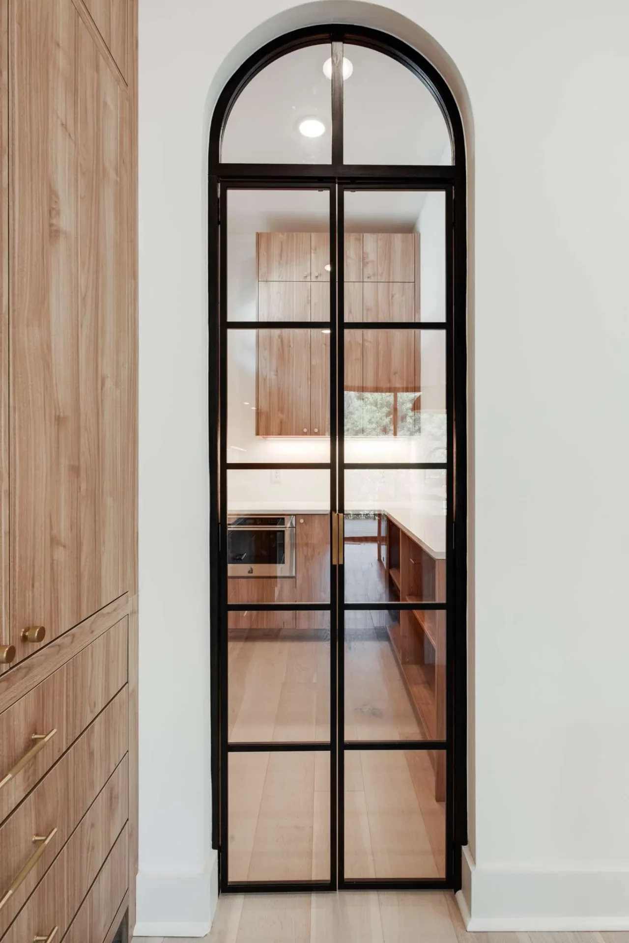 Tall light wood cabinetry beside a black framed interior opening