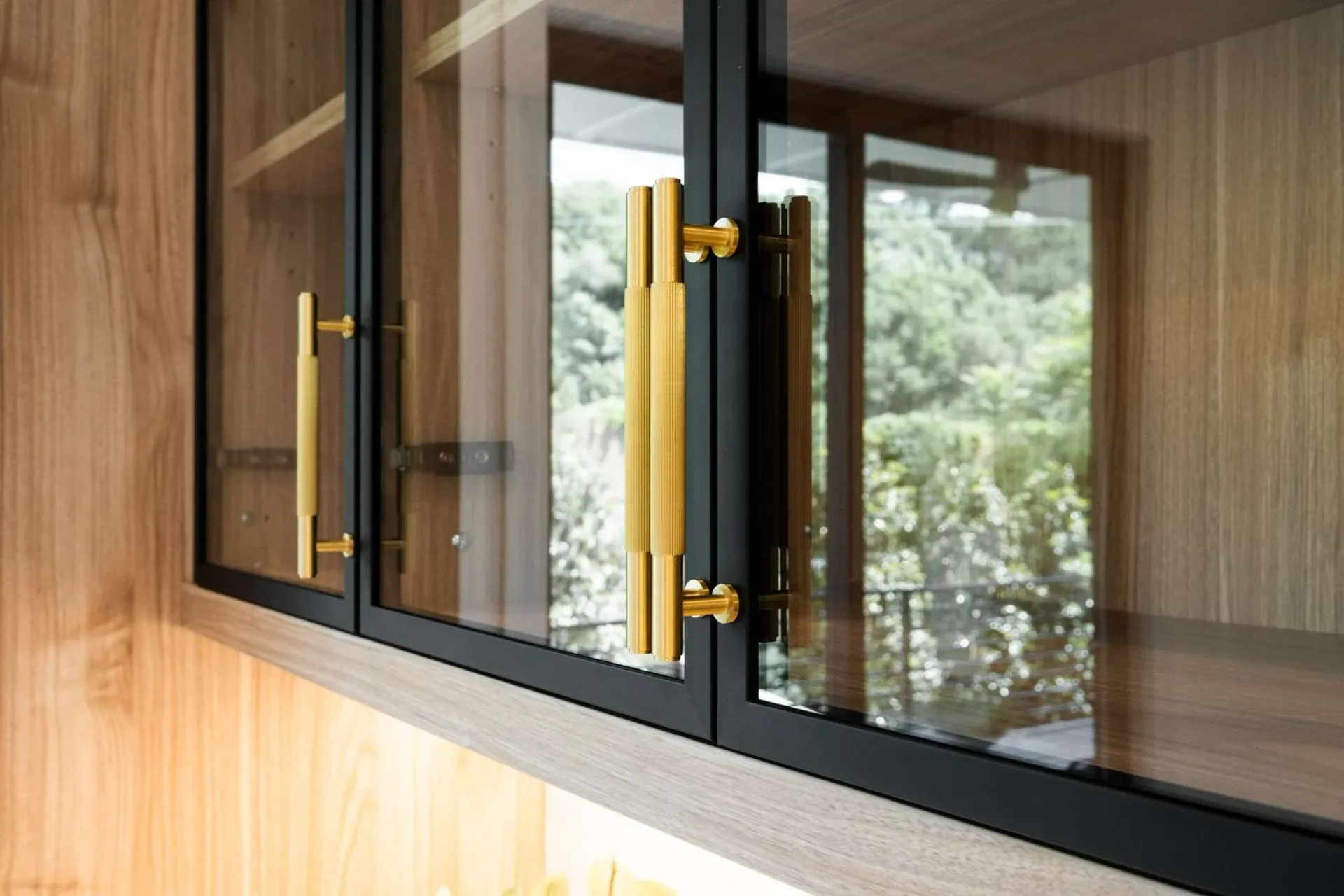 Close view of a black framed cabinet opening within light wood cabinetry