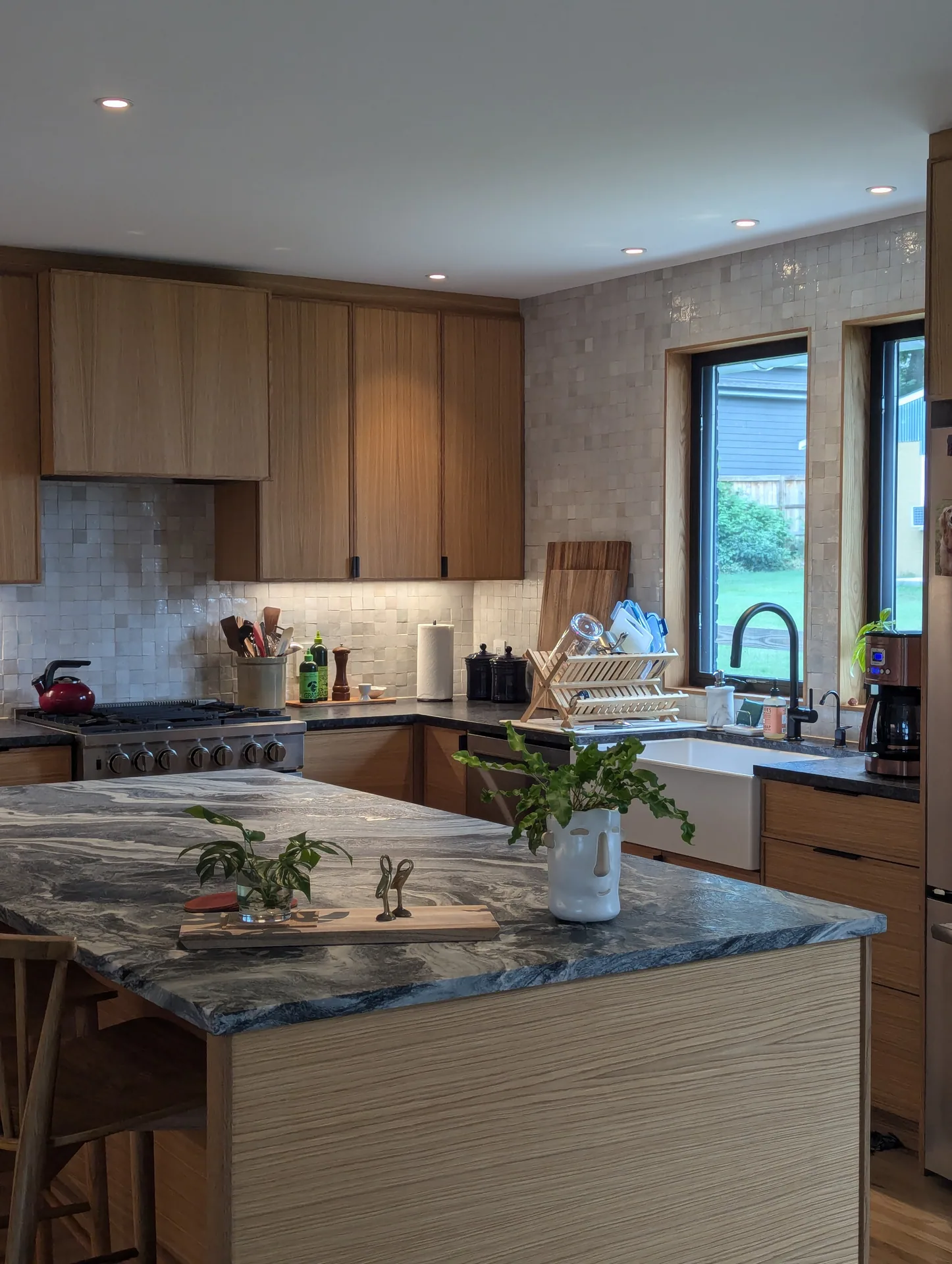 Wood island cabinetry and a patterned gray countertop facing the Mayfield Kitchen range and sink