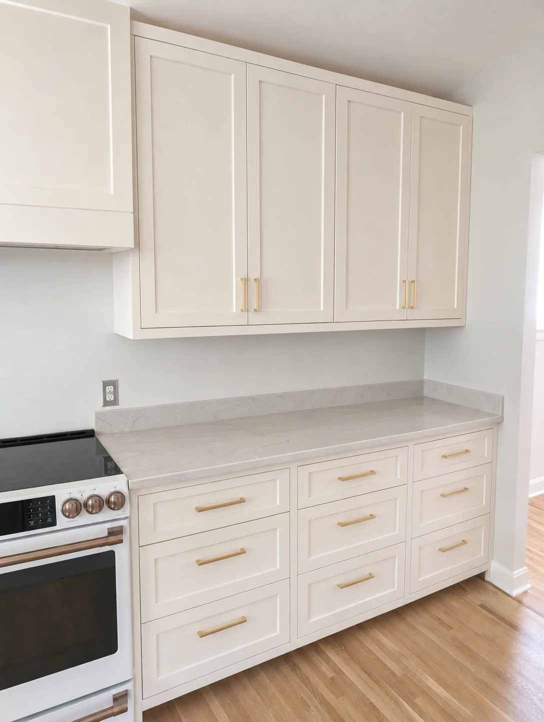 White inset-panel cabinets with brass pulls and a matching hood enclosure in the Miller Kitchen