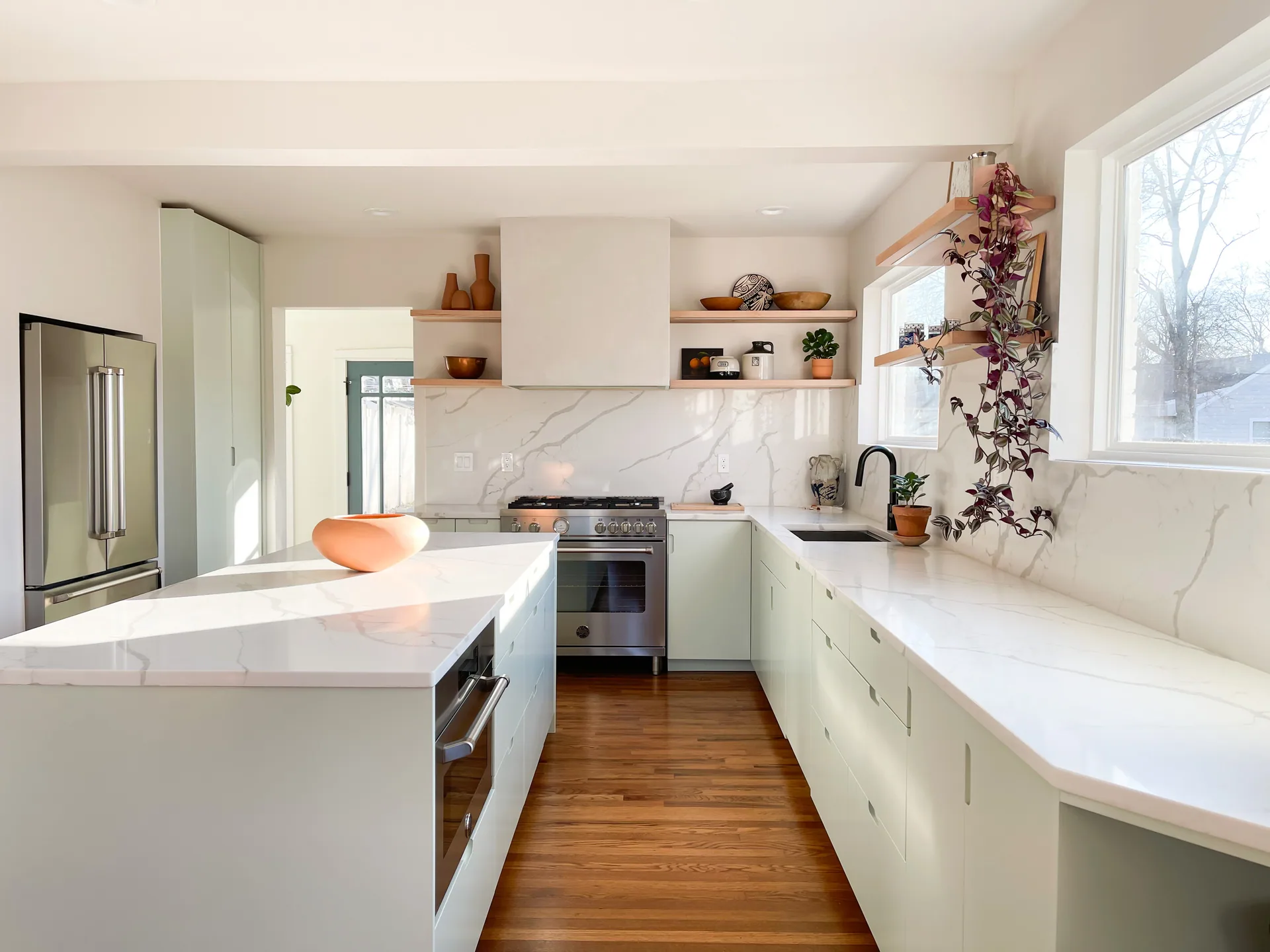 Pale green cabinetry and a white island facing the range at Morton
