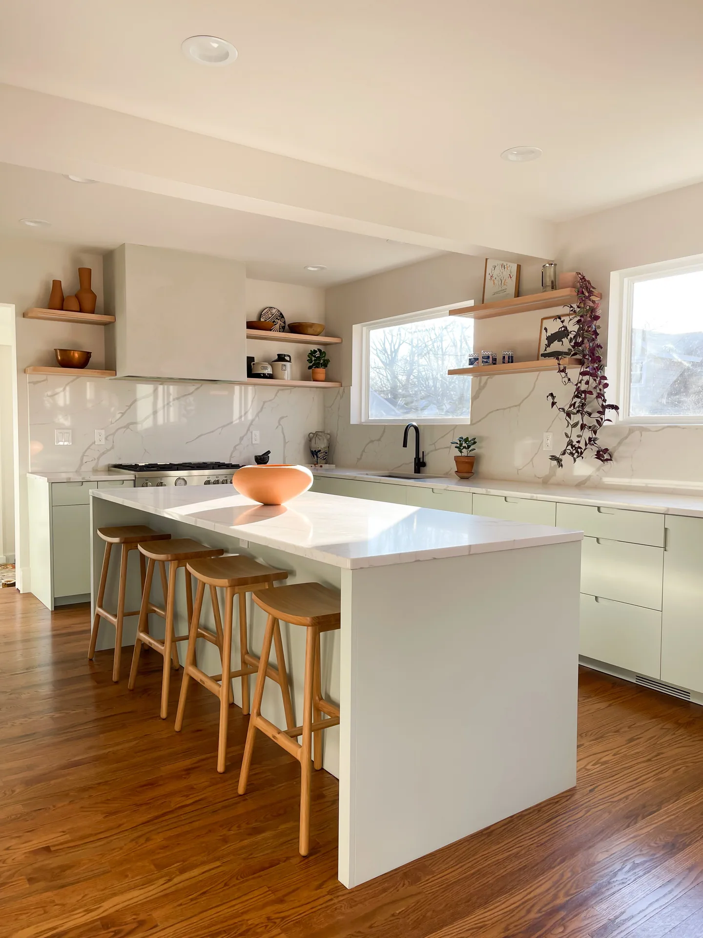 Pale green island with a white counter and four wood stools at Morton