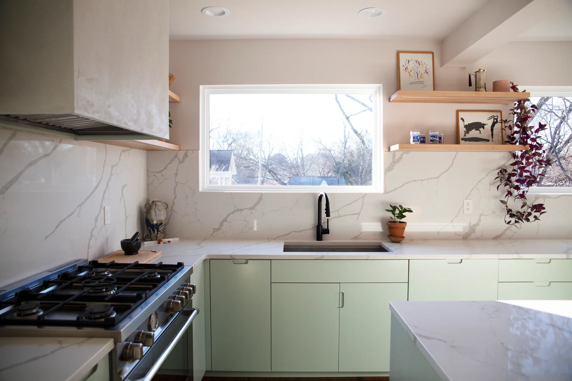 Morton sink wall with pale green drawers, veined white surfaces, and wood shelves